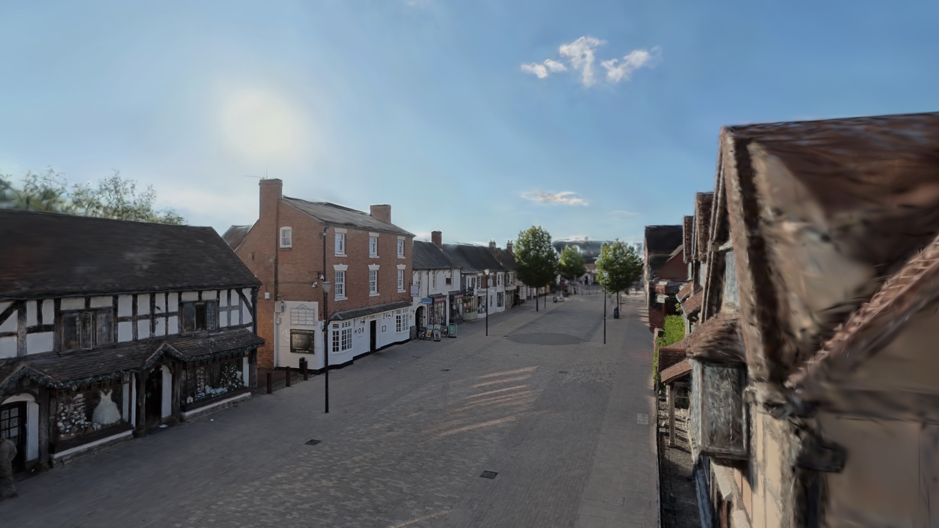 Henley Street in Stratford-upon-Avon as a 3D Gaussian splat scene on Apple Vision Pro: timber-framed shops, a paved pedestrian street, lamp posts and a blue sky